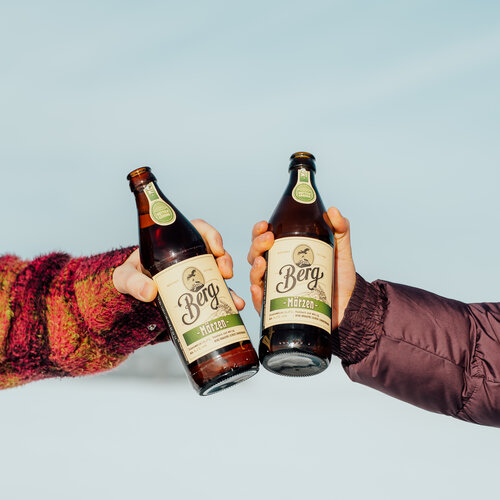 Zwei Menschen stoßen mit Bier an