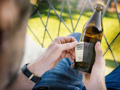 Ein Mann zieht ein Etikett von einer Flasche ab