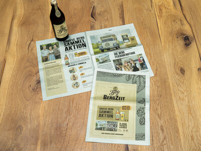 Eine Zeitung mit Bier steht auf einem Holztisch
