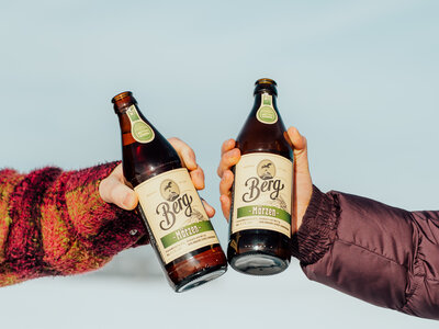 Zwei Menschen stoßen mit Bier an