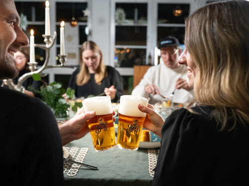 Eine Gruppe von Menschen stößt mit Bier an und feiert gemeinsam einen besonderen Moment.