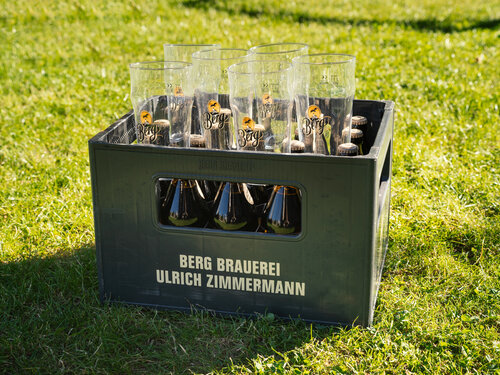 Eine Bierkiste mit Gläsern steht auf einer Wiese
