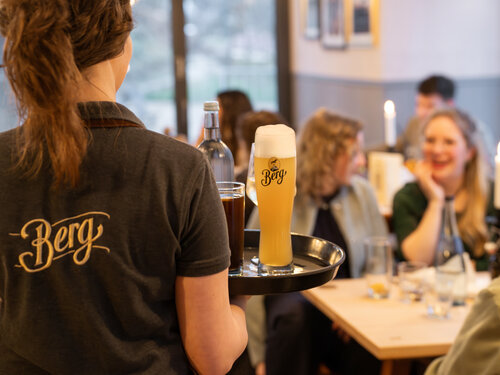 Bedienung im WinterGartenHaus bringt Getränke und Berg Bier an den Tisch