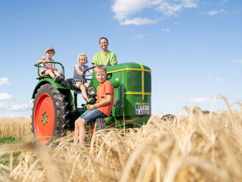 Bauern-Familie auf dem Traktor am Gerstenfeld