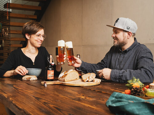 Zwei Personen stoßen mit einem Bier an