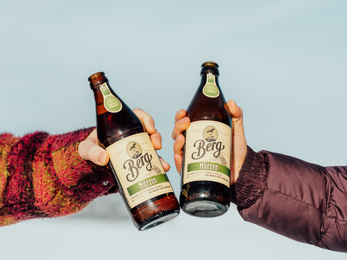 Zwei Menschen stoßen mit Bier an