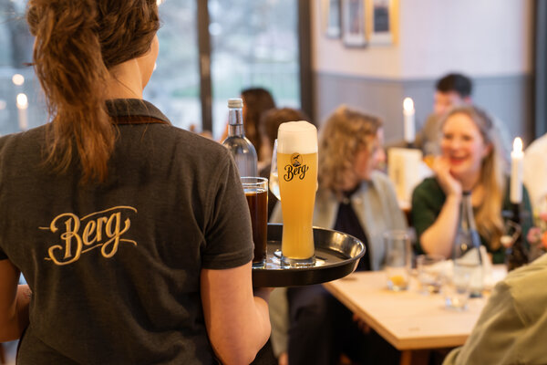 Bedienung im WinterGartenHaus bringt Getränke und Berg Bier an den Tisch